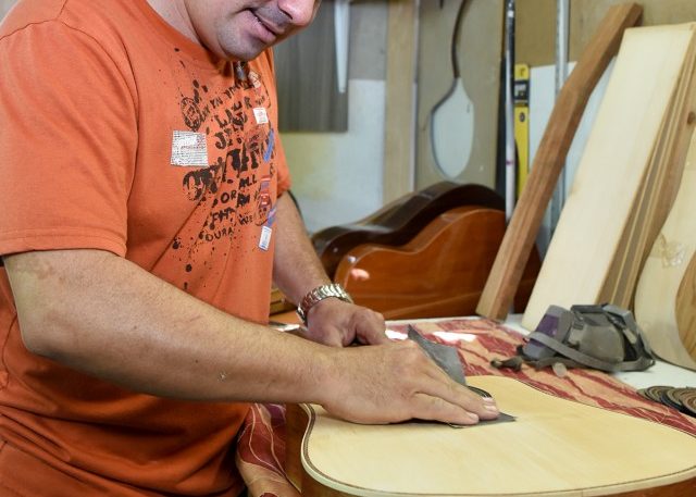 Leandro uses sandpaper to smooth down the body of the instrument