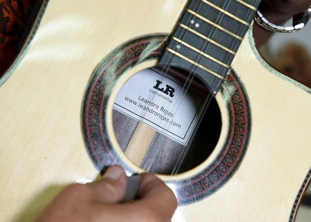 Leandro places a label with his name and website address inside of the instruments he makes