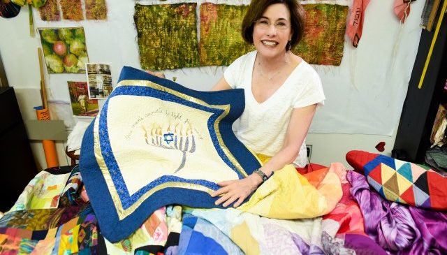 A quilt featuring a menorah, a candle holder central to Hanukkah, the Jewish Festival of Lights